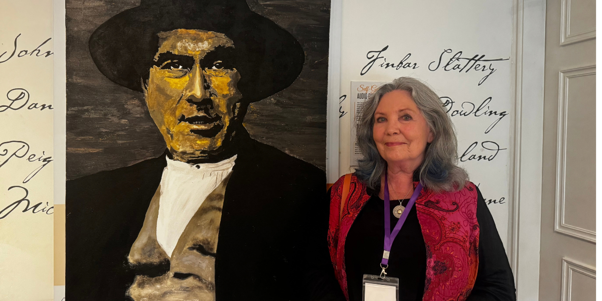 Festival artist Nuala Hayes with a portrait of Éamon Kelly in the exhibition.